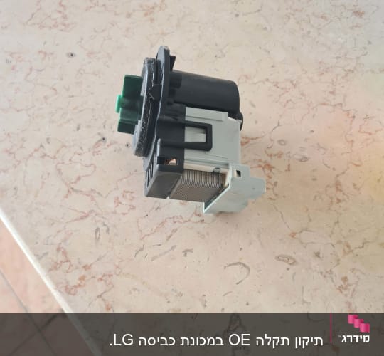 רכיב חשמלי עם חיבורים ירוקים ושחורים על משטח שיש